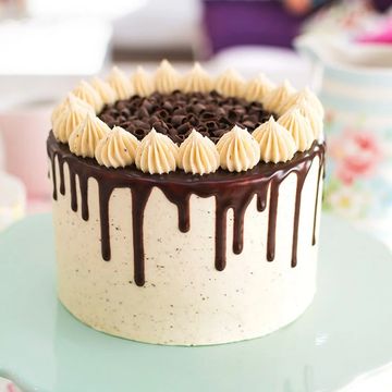 A beautifully decorated cake with chocolate drips and cream dollops.