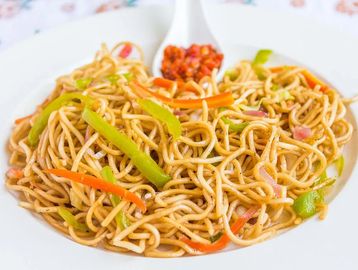 A plate of vegetable chow mein with bell peppers and carrots.