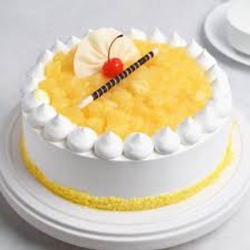 A round cake topped with yellow fruit, cream, and a cherry.