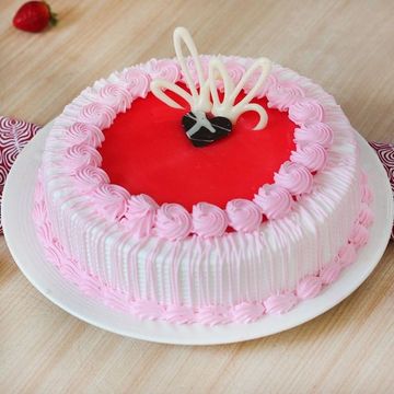 Round cake with pink and white frosting and a decorative heart on top.