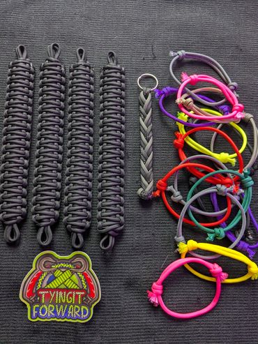 Handmade paracord wristbands and colorful bracelets arranged on a black surface.