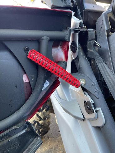 Close-up of a red coil spring attached to a vehicle frame.