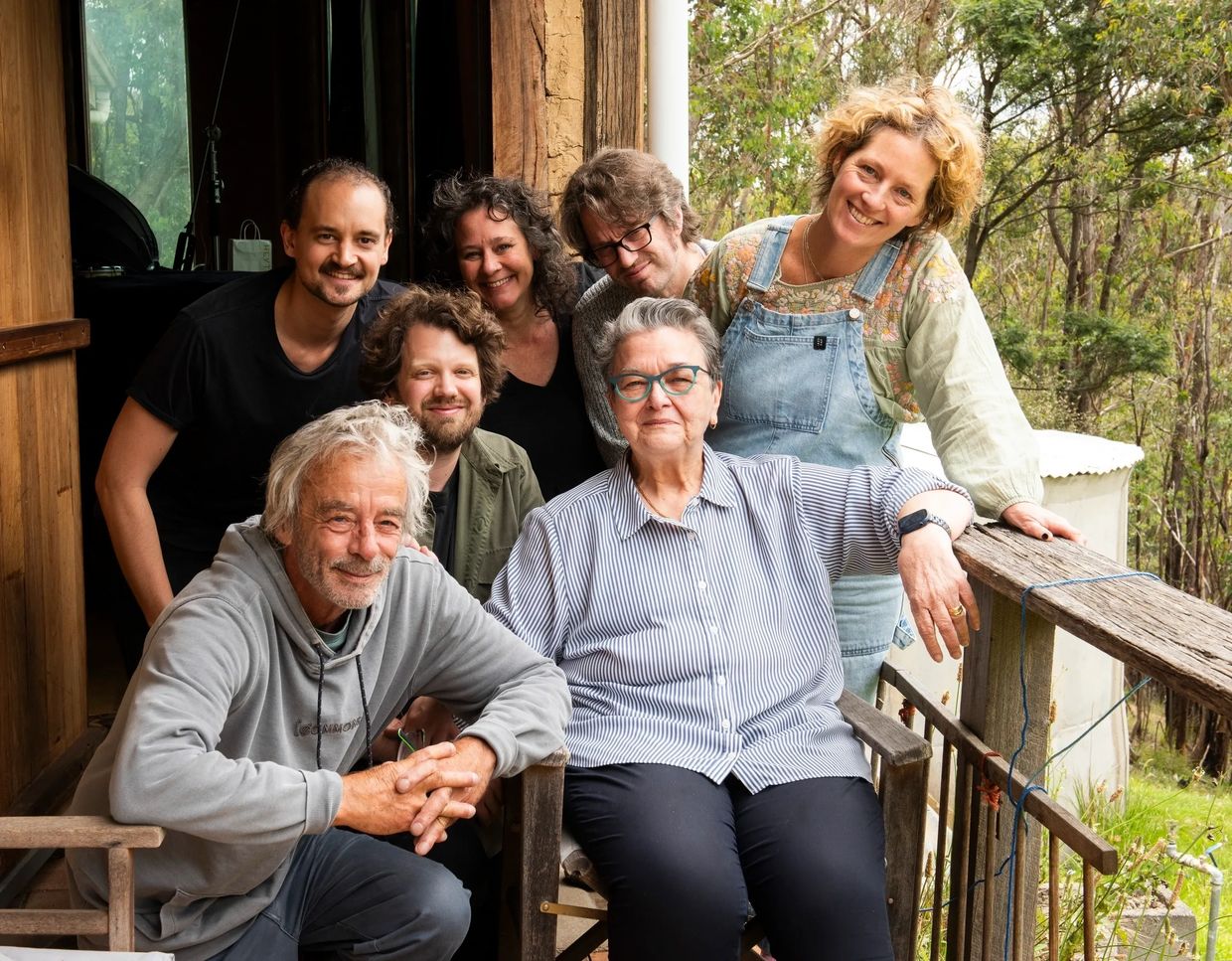 A happy group of seven people posing outdoors on a porch.