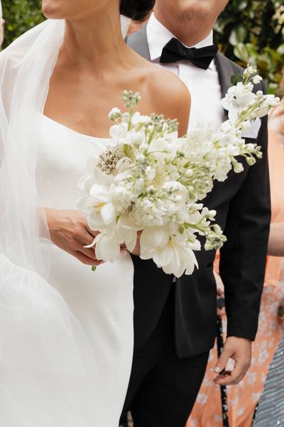 A bride in her wedding dress holding flowers.