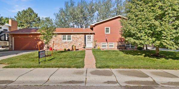 Sunny suburban house with a well-kept lawn and a for sale sign.