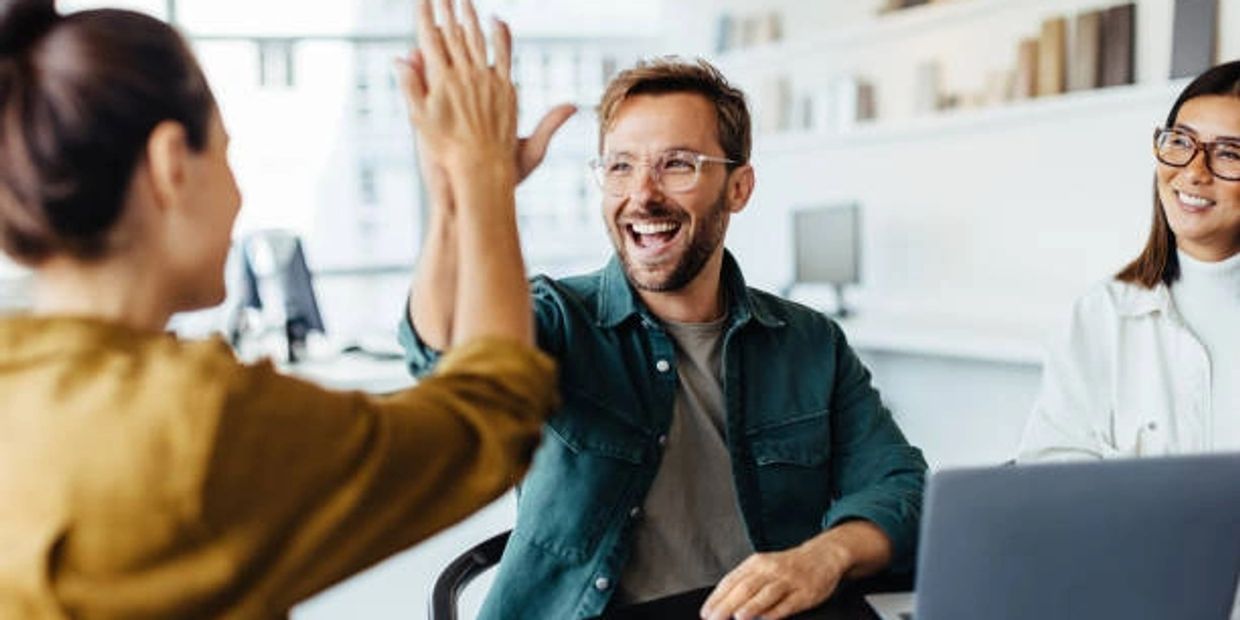 Colleagues sharing a joyful high five in a modern office space.