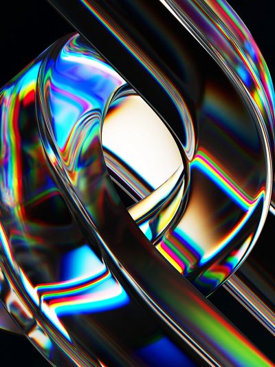 Colorful abstract glass sculpture with rainbow reflections on a black background.