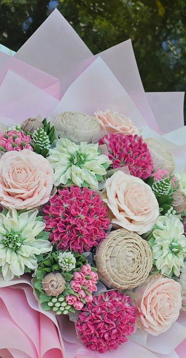 Elegant bouquet with pink, white, and cream flowers wrapped in soft pink paper.