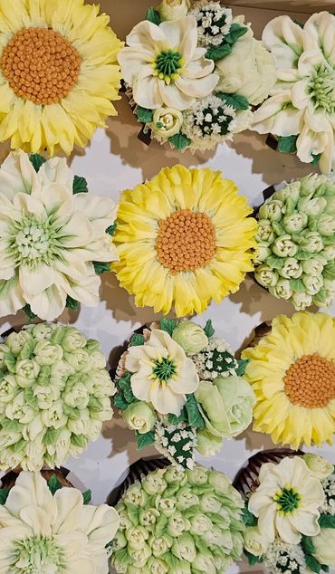 Beautiful cupcakes decorated with intricate yellow and white floral designs.