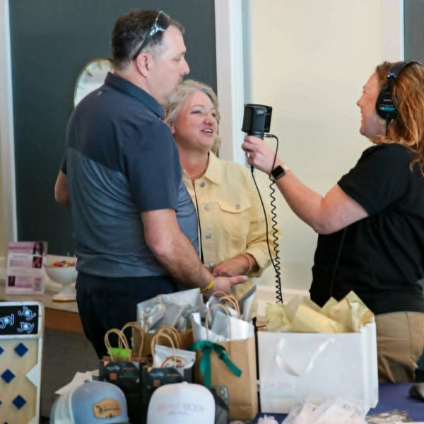Two people being interviewed by a woman with a microphone.