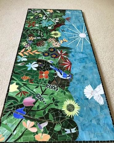 Colorful mosaic artwork with flowers, birds, and a sun.