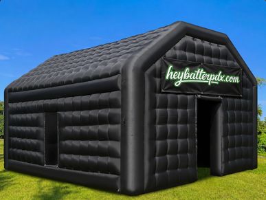 Black inflatable structure with 'heybatterpdx.com' sign on top.