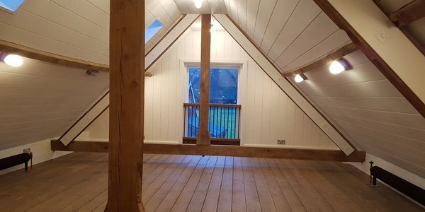 Empty attic with wooden beams and a window.