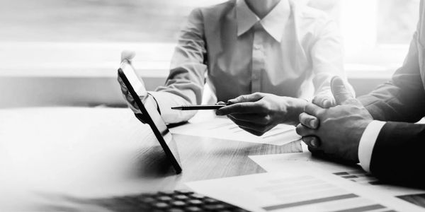 Two business professionals discussing data on a tablet at a desk.