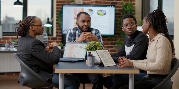 Four colleagues engaged in a discussion in a modern office setting.