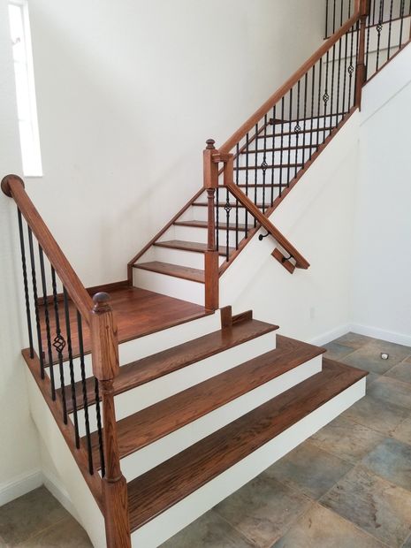 Custom solid treads with white risers featuring oak hand railing with iron balusters.