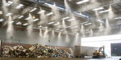 Large indoor waste facility with piles of garbage and machinery.