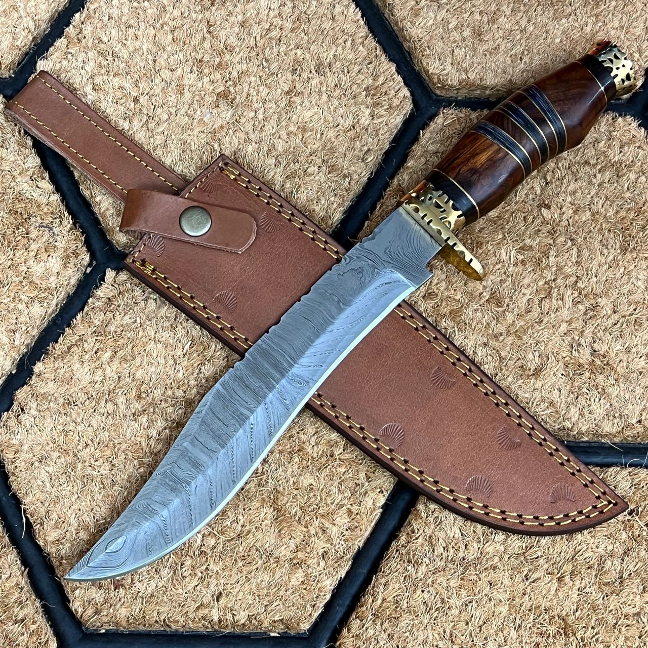 The ASH HC44 Machete is a versatile and lightweight Kukri knife that is ideal for outdoor activities, such as camping and hiking. Its compact size and durable construction make it an ideal tool for a wide range of tasks, from chopping firewood to preparing food.  Get ready to tackle any task with this premium Kukri knife. Measuring 14 inches in overall length and 9 inches in blade length, this knife features a stunning Damascus steel blade with a Rockwell hardness of 55-58. The handle is crafted from a combination of brass guard, brass spacers, and elegant walnut wood, providing a comfortable grip. The knife is housed in a sturdy cowhide leather sheath with a belt loop for easy carry, and weighs approximately 480 grams. Whether you're an outdoorsman, collector, or simply looking for a reliable tool, this Kukri knife is sure to impress. 