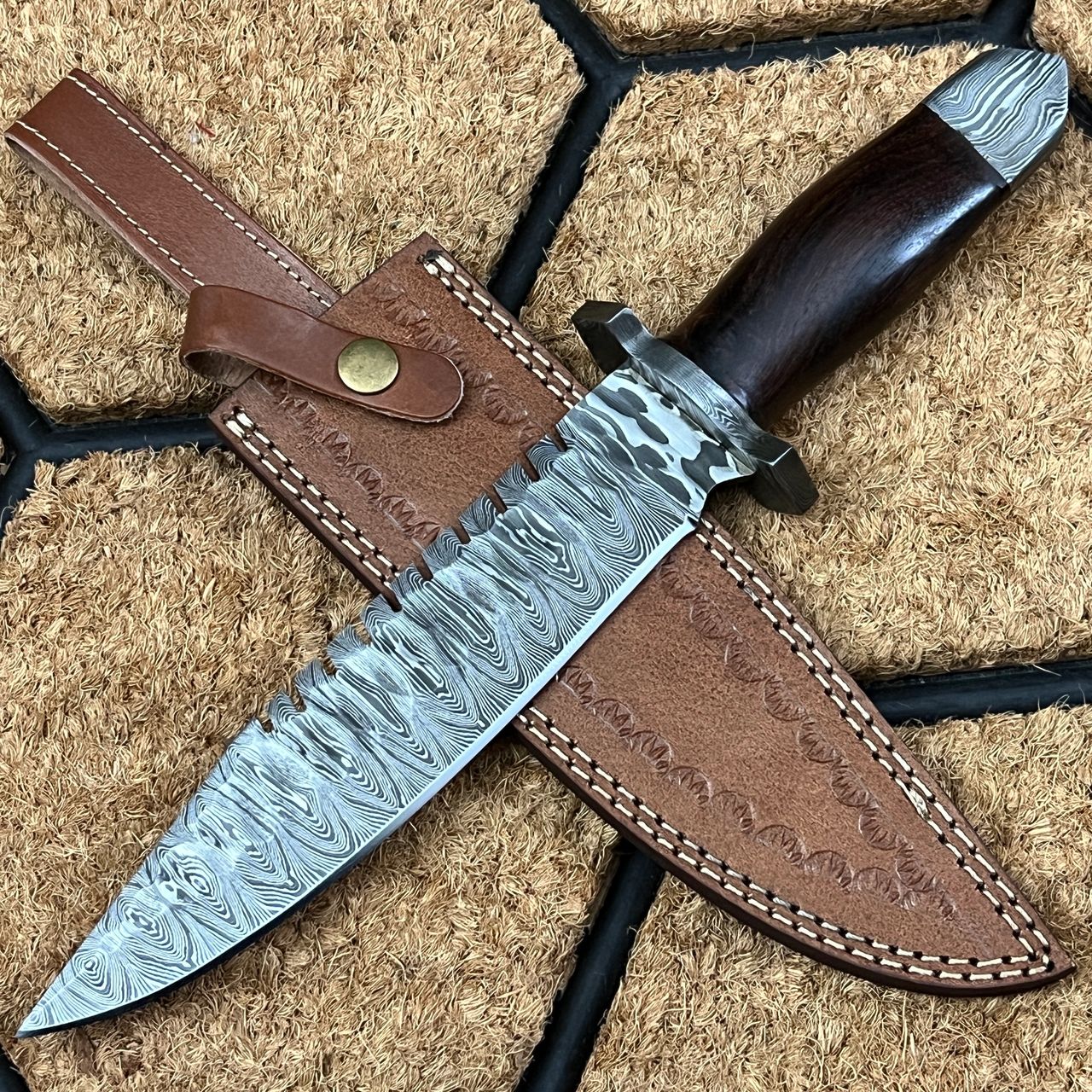 The 8.5 inches knife's clipped point is extremely useful for tasks like skinning and cleaning animals. It's like having a smaller knife, but with all the advantages of manoeuvrability and control that comes with it.  Blade has beautiful patterns and because of the hardness of the inner core, it will keep its edge for longer. The knife's added weight from the damascus steel pommel makes it more manageable.   Rosewood is used in the majority of knives since it is a beautiful wood that is also quite sturdy and durable, due to its exceptional durability, rich colour, and pleasant aroma.  As a tool that may be used in a variety of situations, this knife earns a perfect score of five stars for its use on hikes, backpacking trips, and other outdoor adventures.   With the serrated edges on its back, that have a toothed or saw-like edge ground into the cutting surface. These should be used with a sawing action, much like a tiny saw. They excel at slicing through belts and ropes, fabrics, and other textured materials.