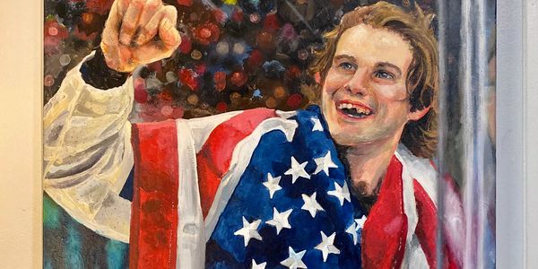 Person draped in American flag, smiling and pointing upwards.