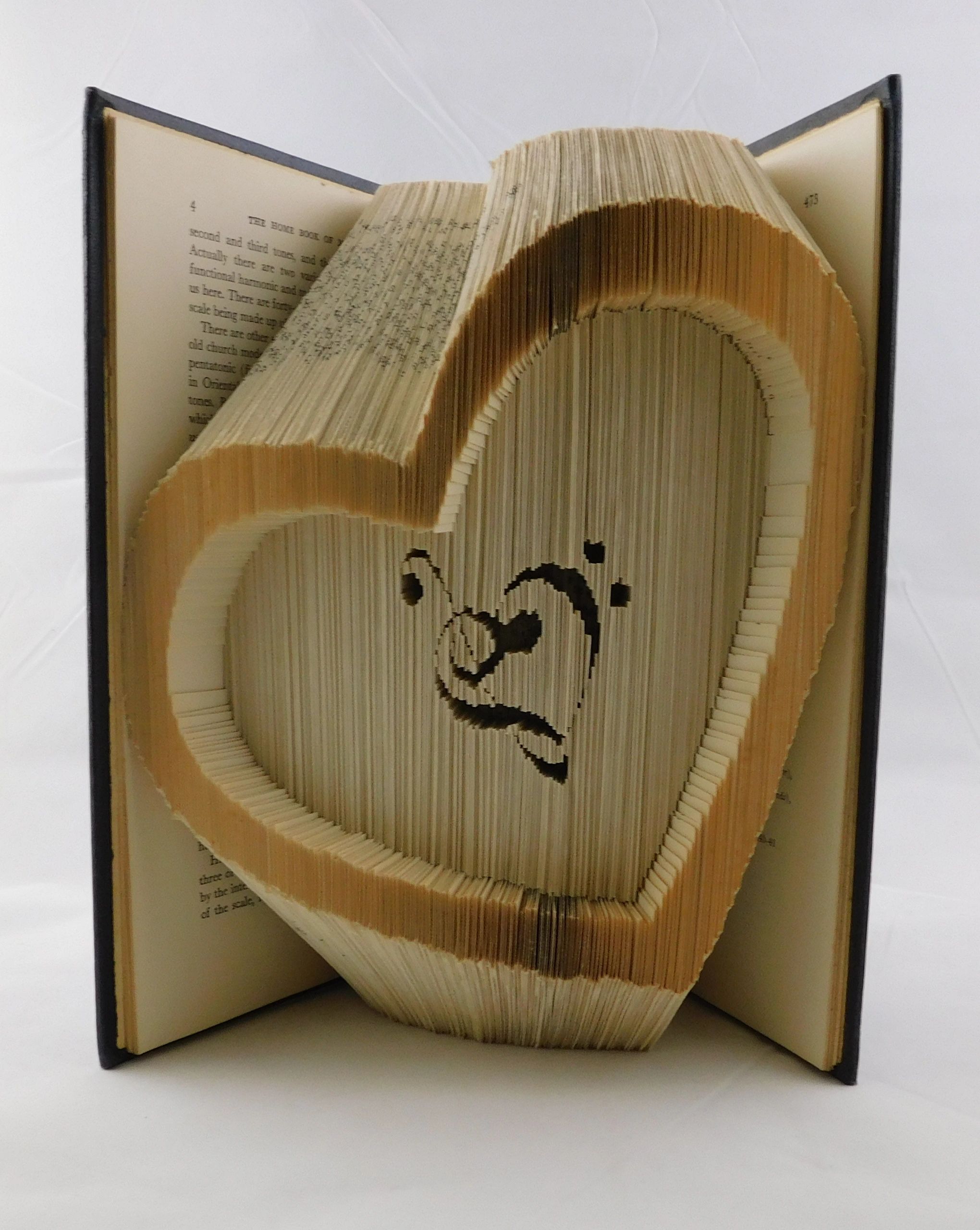 A tilted heart folded from the pages of a rescued book with a musical heart within it.