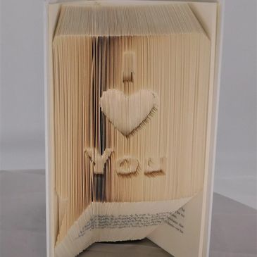 A rescued book that is folded in the shape of a word bubble with the words "I heart You" inside it