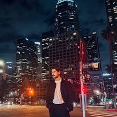 Man standing on a city street at night with tall buildings.
