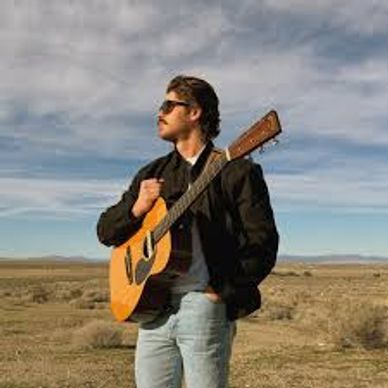 Man with guitar in open landscape.