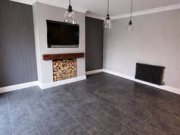 Modern empty room with gray tiles, wood logs, and hanging lights.
