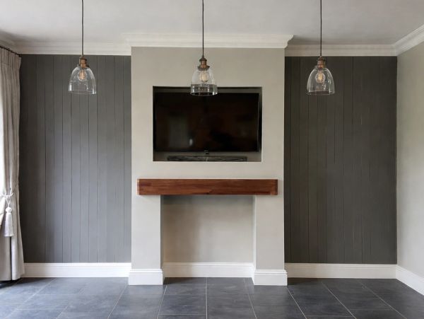 Modern living room with gray walls, mounted TV, and pendant lights.