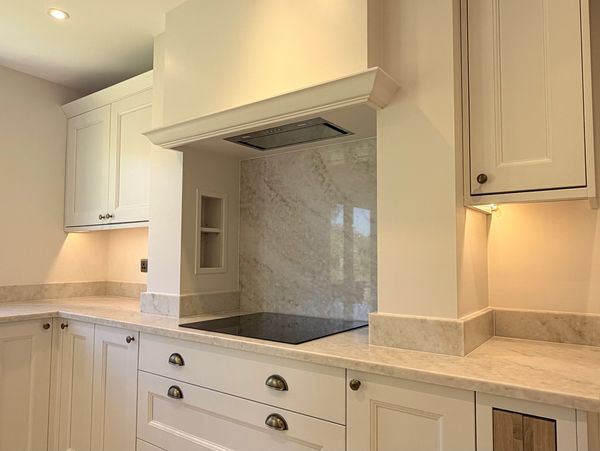 Modern kitchen with marble countertops and white cabinetry.