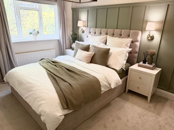 Cozy bedroom with beige bed, green accents, and soft lighting.