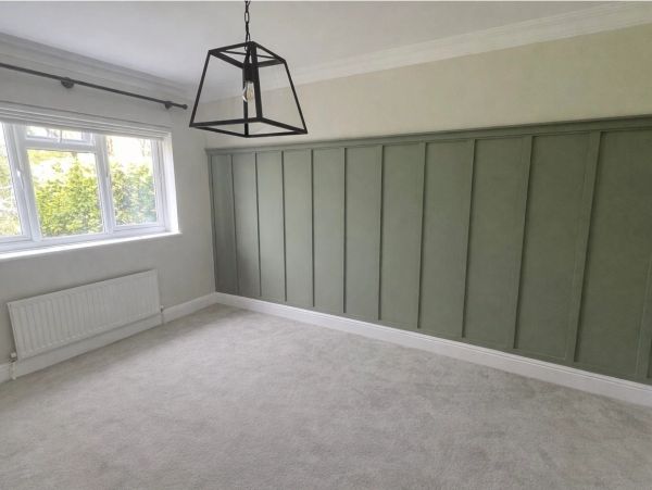 Empty room with green panel wall and large window.