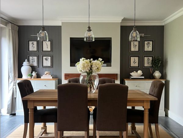 Elegant dining room with wooden table, dark chairs, floral centerpiece, and wall art.