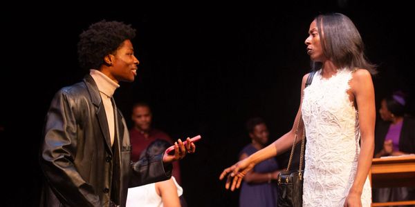 Two people engaged in a dramatic conversation on stage during a play.