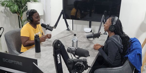 Two people recording a podcast in a studio with microphones and headphones.