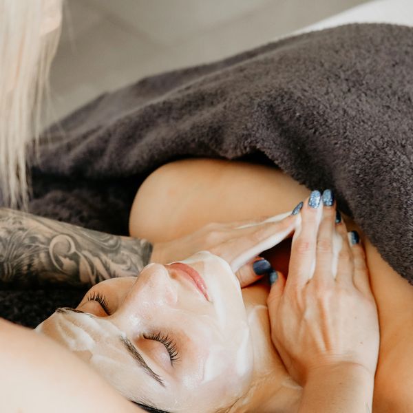 A woman receiving a relaxing facial treatment under a brown towel.