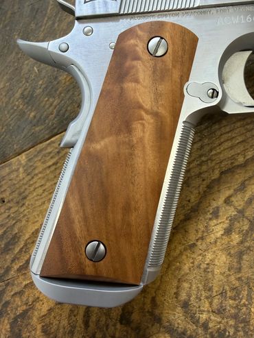 Close-up of a wooden grip on a silver handgun.