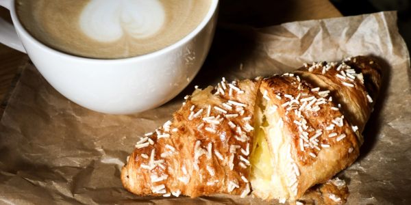 A cup of coffee and croissant with text inviting tennis lovers to decide.