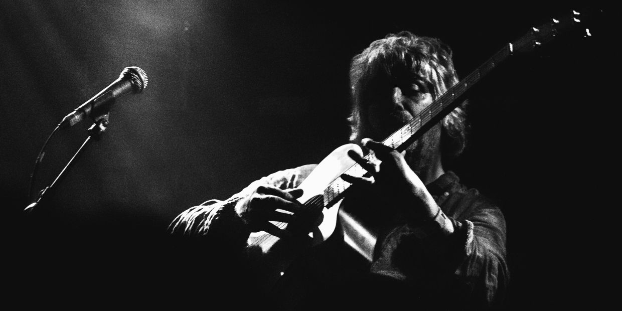 Black and white photo of a musician playing guitar on stage.