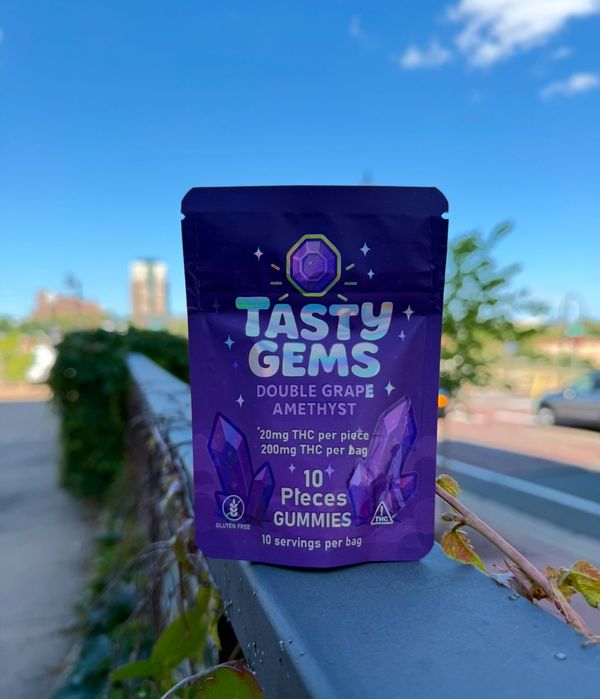 A purple bag of Tasty Gems Double Grape Amethyst THC gummies outdoors.