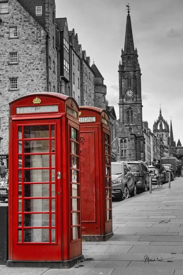 Two red vintage British phone booths are in the foreground with a black and white image of the city 