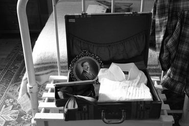 Black and white of 1940s bedroom and open suitcase.
