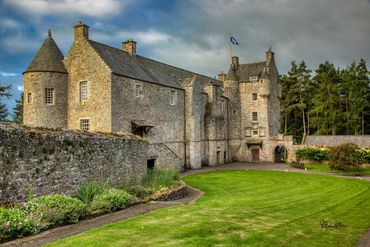 A lush green lawn in the foreground leads to a large, well preserved, 15th century castle in the Bor