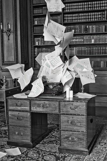 A desk in a library with papers flying upward from the desk.