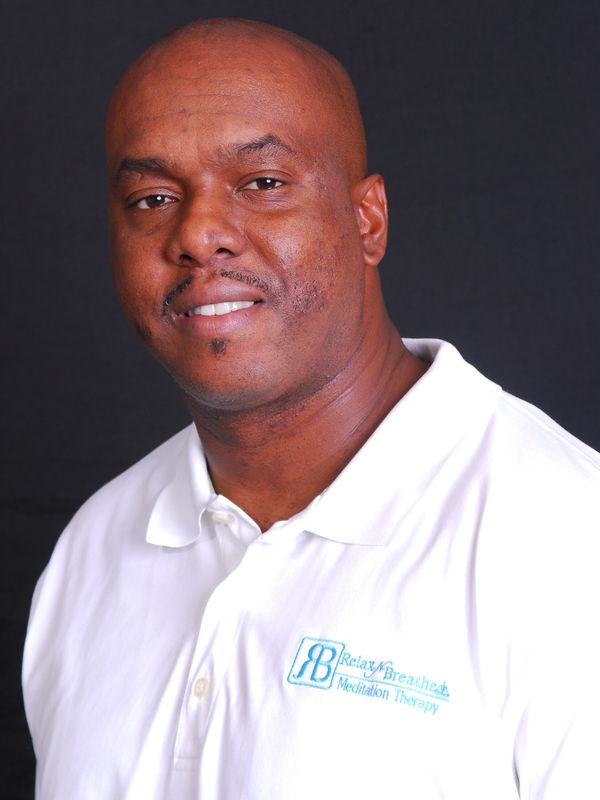 Man smiling wearing a white polo shirt with a Relax &amp; Breathe logo.