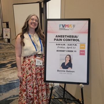 Woman standing next to a conference sign for anesthesia and pain control session.