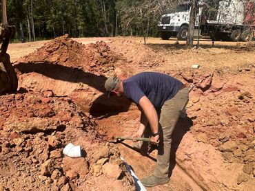 Man digging a trench with a pickaxe.