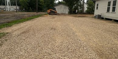 Gravel driveway next to houses and a bulldozer.