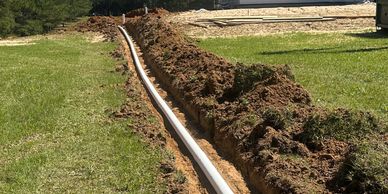 Pipe laid in a trench on a grassy field.